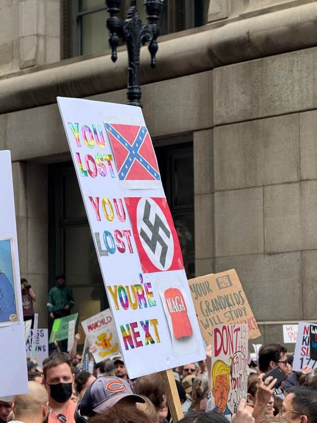 Sign with rainbow lettering:
YOU LOST (next to Confederate flag)
YOU LOST (next to Nazi flag)
YOU’RE NEXT (next to M*GA hat)